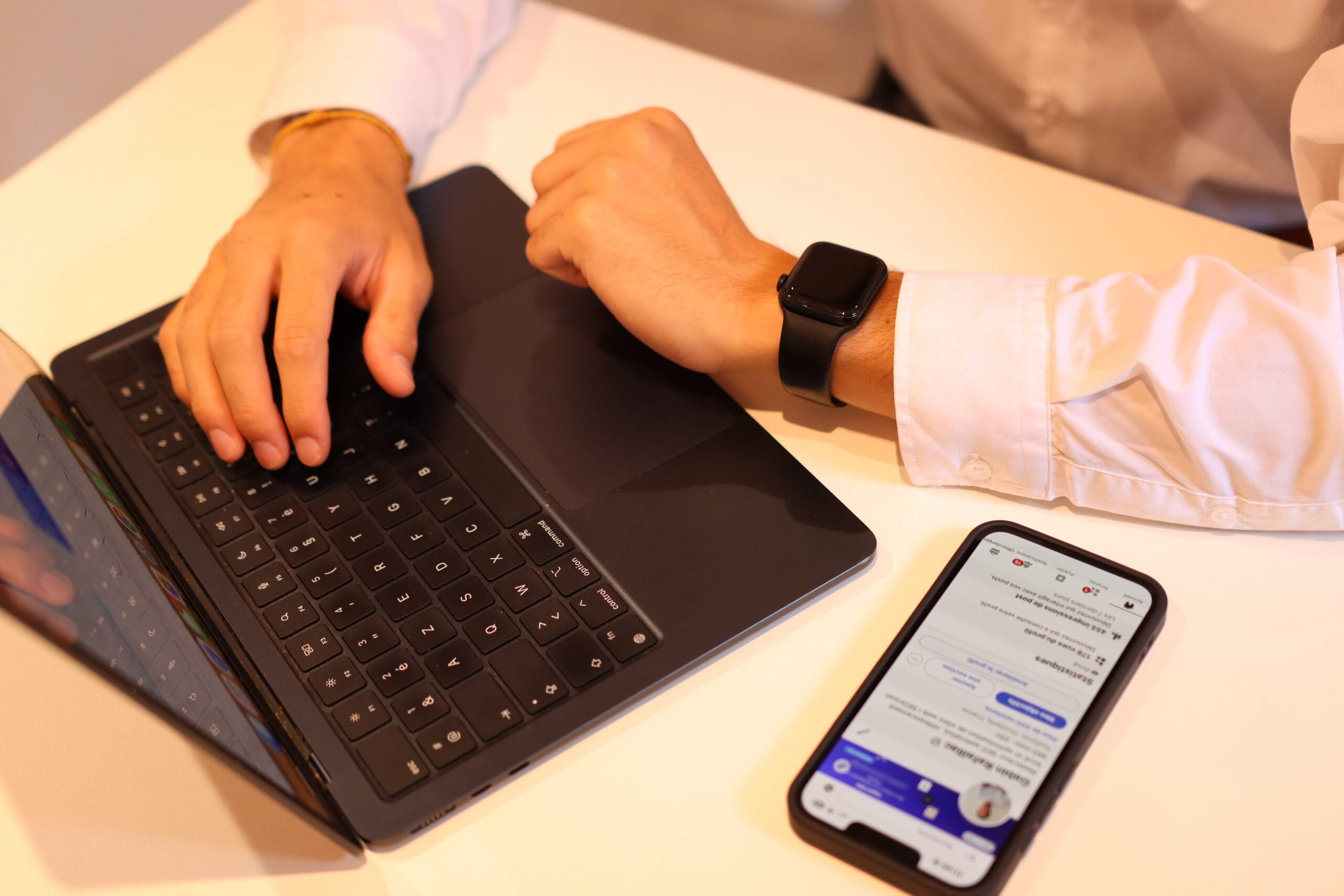 Visuel sur un ordinateur portable ouvert, un smartphone et les bras d'un homme.
